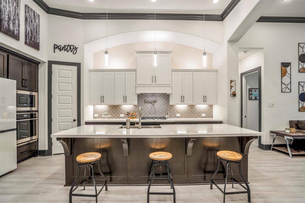 The kitchen boasts a deco wood paneled island with contrasting white cabinets and quartz countertops. Upgraded with built-in stainless steel appliances and a 5 burner gas cooktop, this kitchen is ideal for cooking for the whole family or hosting holidays!