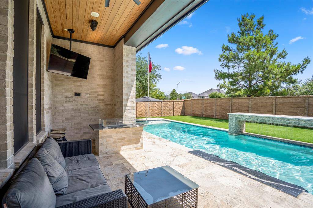 Relax and unwind after a long day in the pool or entertain family and friends! One of the covered patios with a built in fire pit, accented wood ceiling, an outdoor ceiling fan, and recessed lighting.