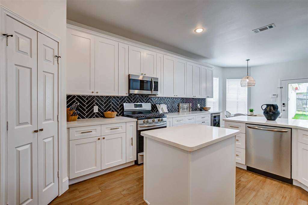 The elegant herringbone tile backsplash adds a touch of sophistication, perfectly complementing the crisp white cabinetry that provides ample storage. Equipped with a gas cooktop, the kitchen makes cooking a breeze, and the spacious walk-in pantry offers an abundance of room for all your kitchen essentials.