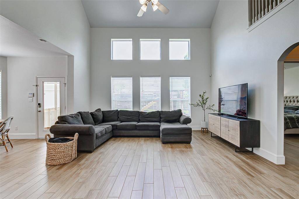The room is bathed in natural light from a wall of stacked windows that overlook the serene backyard, creating an ideal space for family gatherings or entertaining guests.