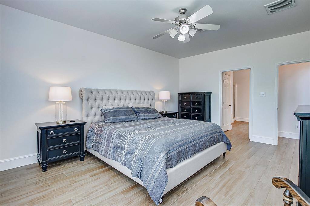 With soaring ceilings, a ceiling fan, gleaming tile floors, and expansive windows that fill the room with natural light, this space exudes a serene and airy ambiance.