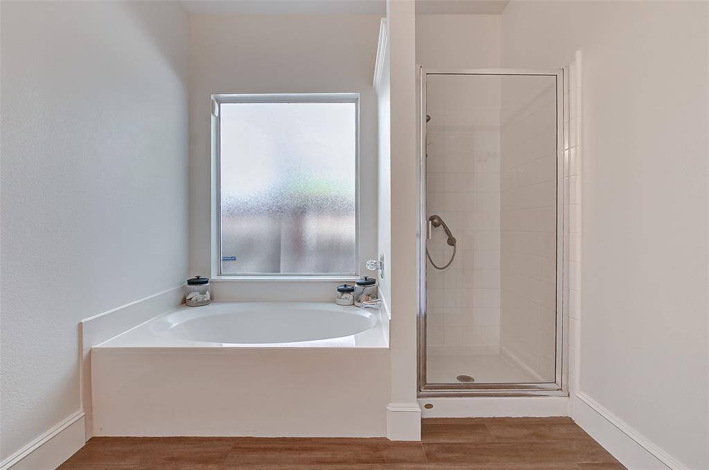 For versatile bathing options, the bathroom boasts a relaxing garden tub as well as a separate walk-in shower, creating a luxurious spa-like experience.