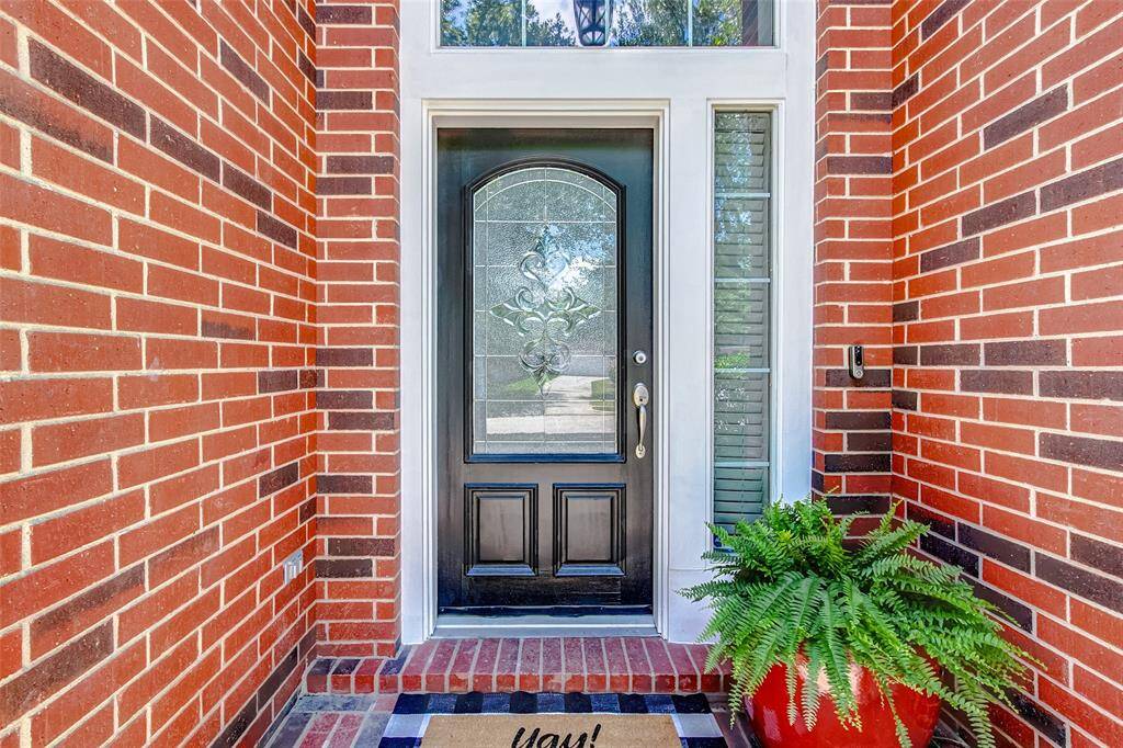 As you approach, admire the timeless brick exterior, the inviting covered entrance, and the stunning mahogany door with leaded glass details that warmly welcomes you inside.