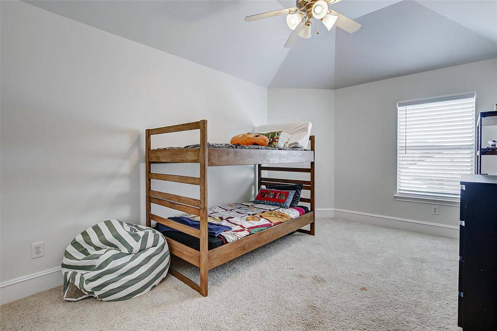 The third secondary bedroom offers ample space, a high vaulted ceiling with a fan, and a large window that fills the room with natural light. Plush carpeting adds warmth, making it a cozy retreat. This bedroom also shares a Jack-and-Jill bathroom.