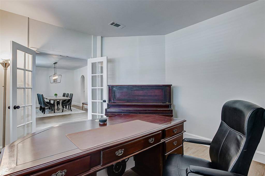 The home office features high ceilings, neutral paint tones, tile flooring accented by thick baseboards, and plenty of space to accommodate your needs.