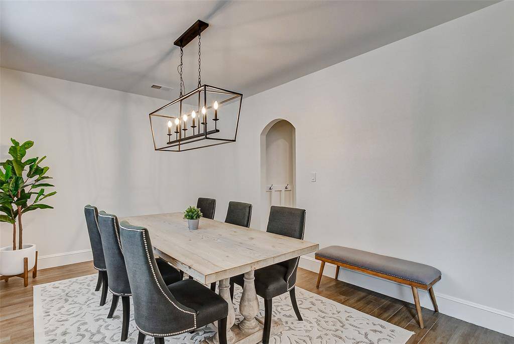 A stunning farmhouse chandelier serves as the centerpiece of this elegant space. An arched doorway conveniently connects the dining room to the kitchen, making it perfect for hosting and entertaining.