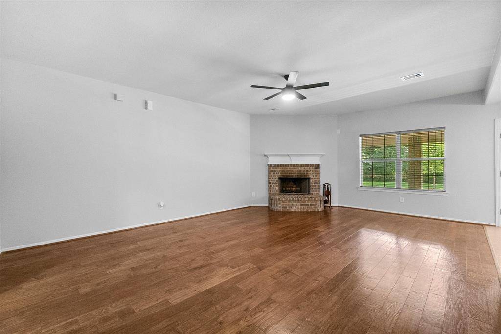Large living room with fireplace and engineered wood floors.