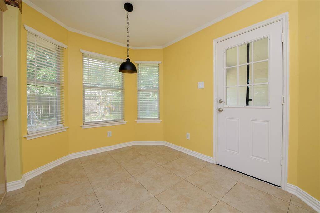 Enjoy meals in this sunny dining corner with a view! Multiple windows bring in the natural light and create a warm, inviting space. The updated pendant light and neutral tile flooring add modern touches to this everyday gathering spot adjacent to the kitchen.