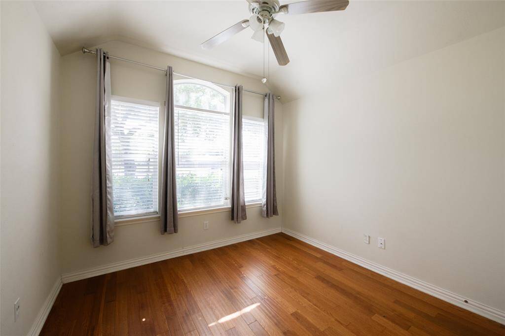 This versatile third bedroom features a dramatic arched window flanked by dual side windows, bringing in abundant natural light. Wood-look flooring and neutral walls offer a clean, flexible space ideal for a home office, nursery, or guest room.