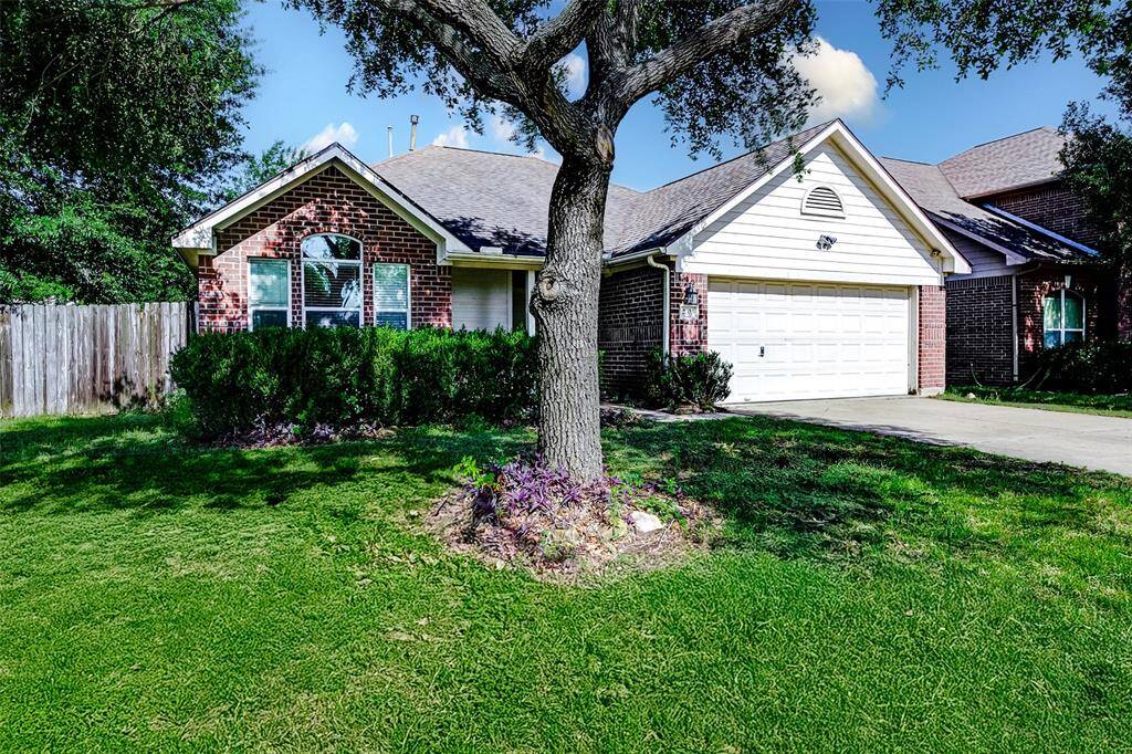 Charming curb appeal! A stately tree anchors the landscaped front yard, complementing the classic red brick and white trim exterior. The large front-facing windows allow natural light to pour in, while a two-car garage and wide driveway offer convenience and practicality.