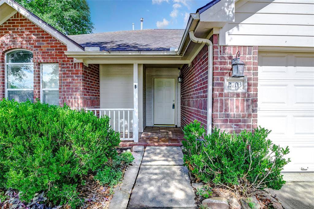 Step up to a cozy covered porch and tiled entryway that invite you into this well-maintained home. A welcoming front door and side lanterns create a warm ambiance, perfect for greeting guests or relaxing with morning coffee. The entry path is surrounded by mature hedges and fresh landscaping.
