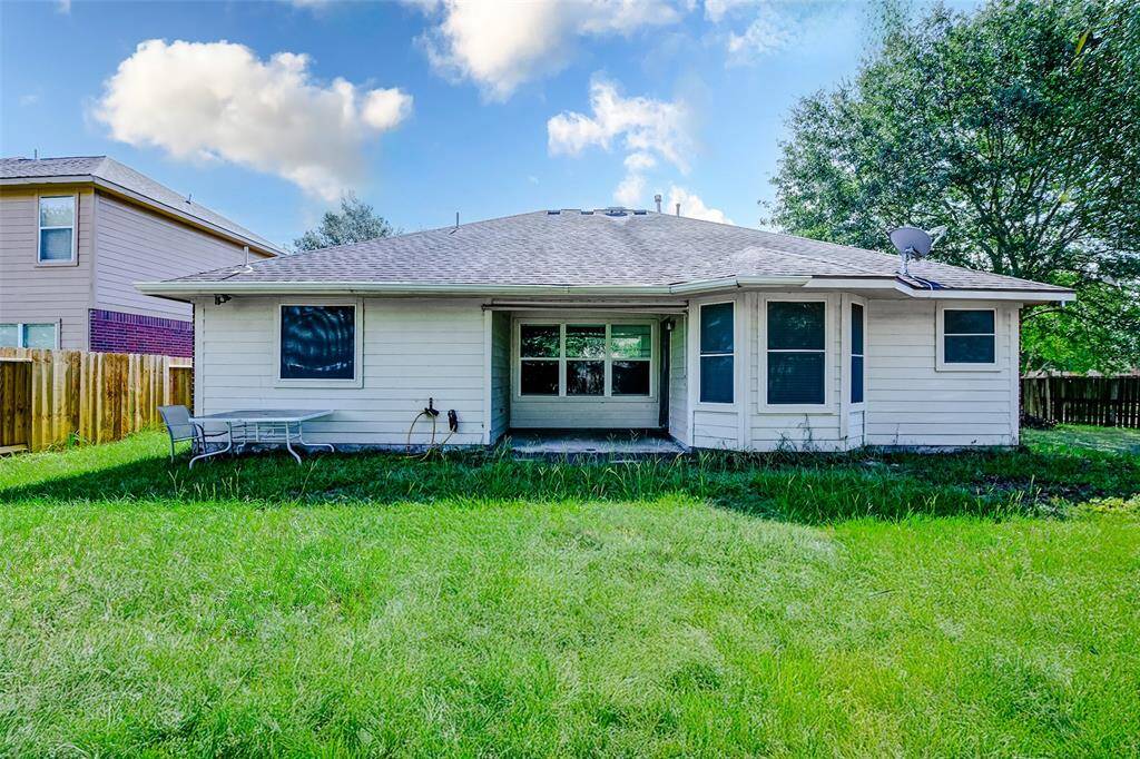 Enjoy the outdoors from your covered back patio, perfect for relaxing or entertaining rain or shine. The home’s rear elevation includes large windows and charming architectural lines, overlooking a spacious, grassy backyard ideal for all ages.