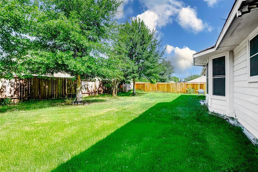 The expansive backyard continues along the fence line with lush grass and established shade trees. Whether you envision a garden, a swing set, or simply room to roam, this outdoor space offers versatility and tranquility.