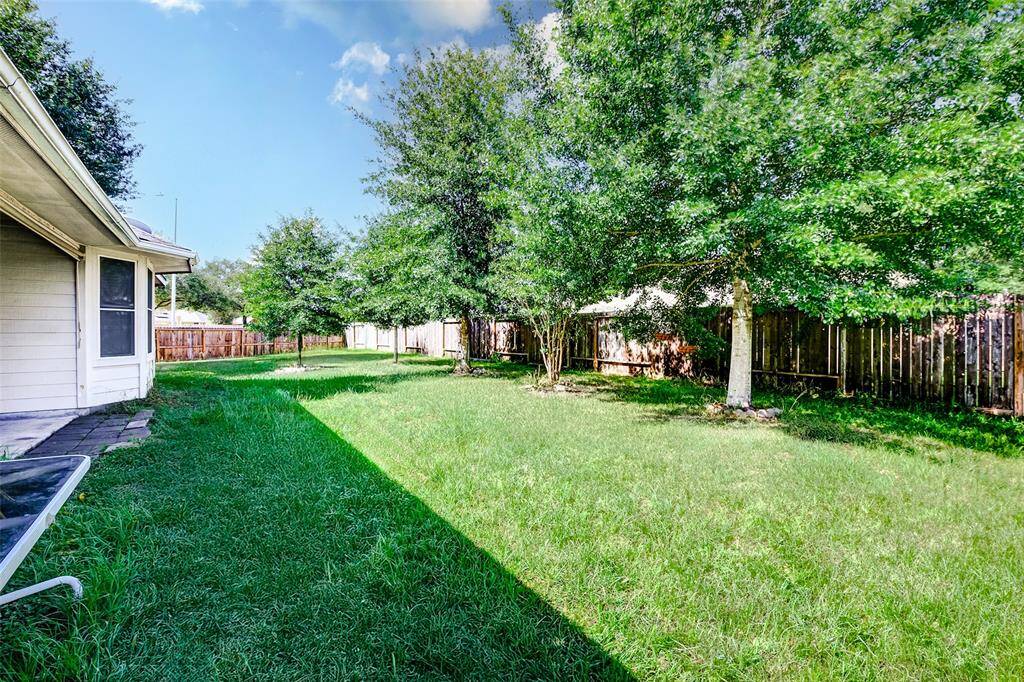 This generous side yard extends the home’s outdoor living potential, offering ample green space along the privacy fence. Ideal for gardening, recreation, or pets, the area feels peaceful and private thanks to the established tree line.