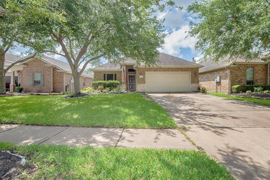 Mature trees frame the front yard, offering shade and a sense of tranquility as you approach the entry. The combination of natural stone and lush landscaping creates a warm and welcoming first impression, setting the tone for the inviting interior that awaits.