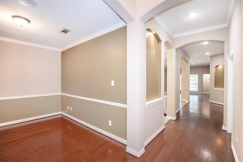Step into the inviting entryway, where gorgeous wood flooring flows underfoot and elegant arched doorways create a sense of architectural charm.