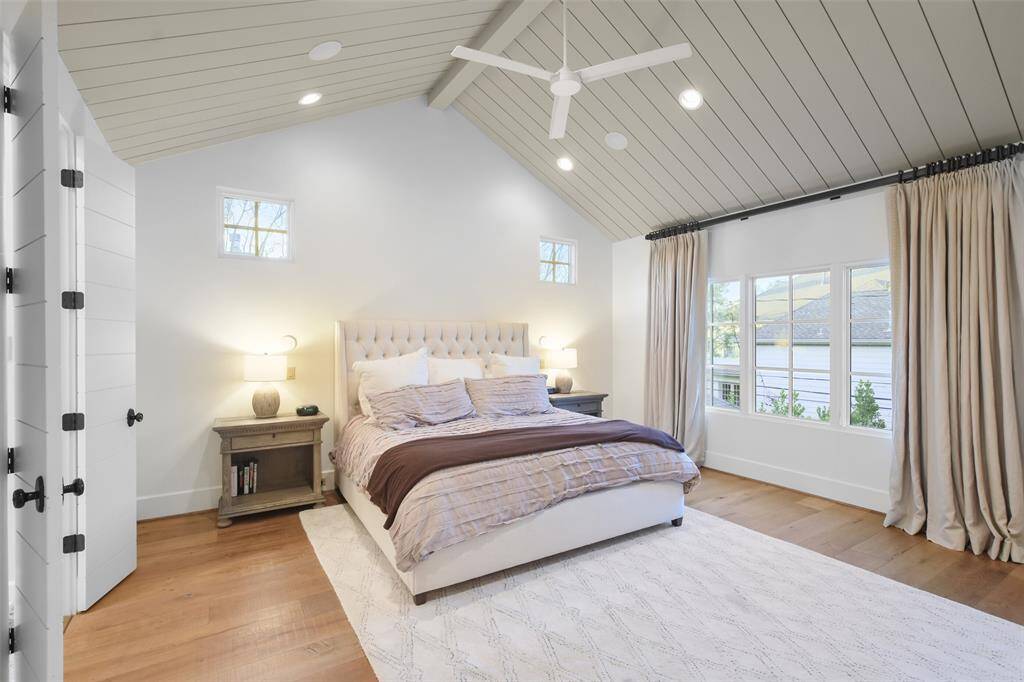 The spacious primary bedroom is a serene retreat that features vaulted ceilings, clad in crisp shiplap. Expansive windows offer views of the backyard and an abundance of natural light.
