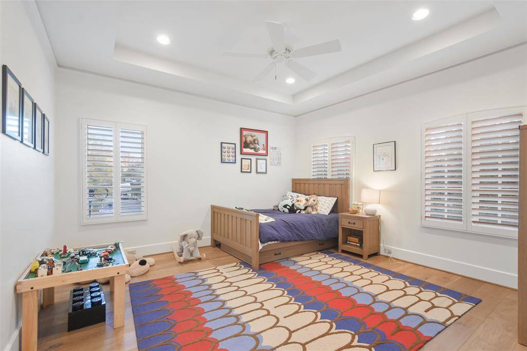 The secondary bedroom is a charming and inviting retreat with a coffered ceiling that adds a touch of sophistication. Window shutters frame the room’s windows, offering both privacy and timeless style. With its tasteful finishes and cozy atmosphere, this bedroom is both functional and refined.