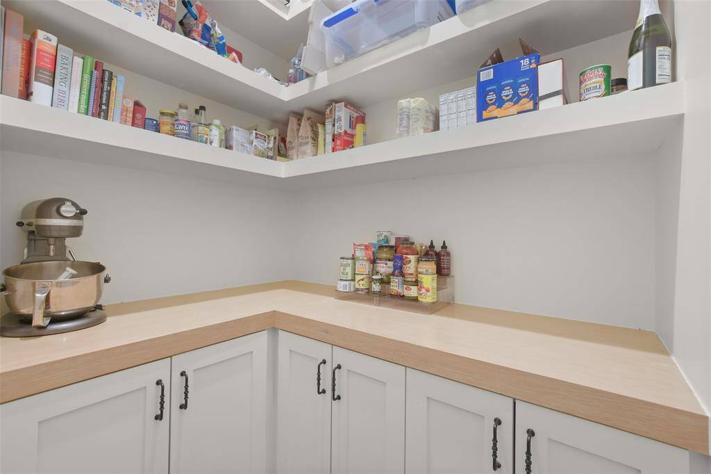 The walk-in pantry is a well-organized space for all your kitchen essentials. Shelves and cabinets line every wall, offering ample space for storage