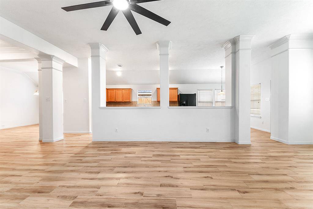 The pony wall provides a seamless transition from the kitchen to the living area. The open floor plan is filled with natural light, thanks to large windows in both the breakfast room and living room. Elevated ceilings, crown molding, and a spacious layout add elegance, while the same tile flooring flows throughout the home for a cohesive look.