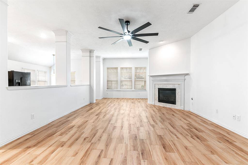 The large living room features a ceiling fan with remote control and a gas fireplace that was recently refaced with white mantle, complemented by a perfect entertainment wall.