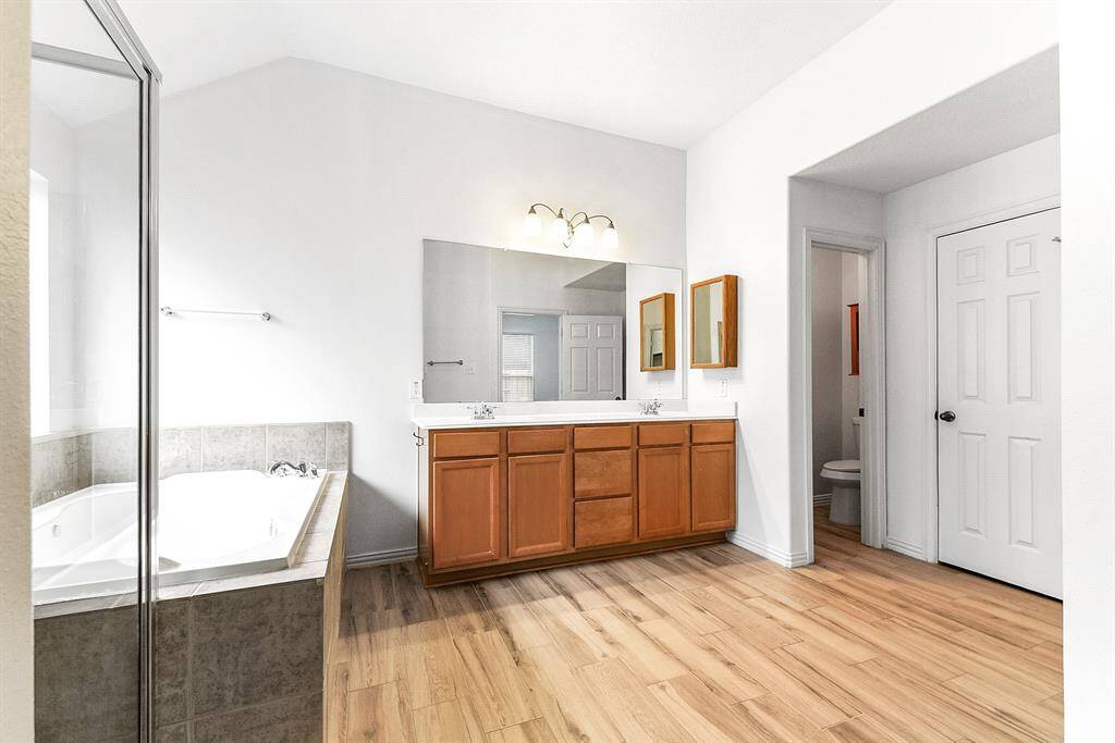 The primary en suite bathroom features a separate jetted tub and walk-in shower, double sinks with plenty of counter space, and ample storage. It also includes a huge wardrobe closet and a linen closet for added convenience.