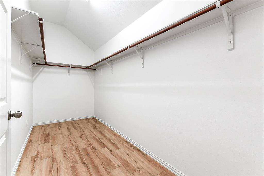 The large walk-in wardrobe closet features three sides of rod space for hanging clothes.