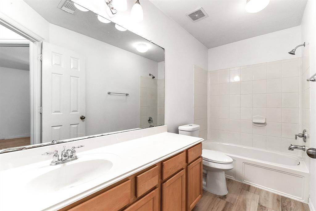 The guest bathroom on the main floor features a three-piece layout with a tub and shower combo, plus a full vanity cabinet providing both convenience of more prep space and ample storage for everyday essentials.