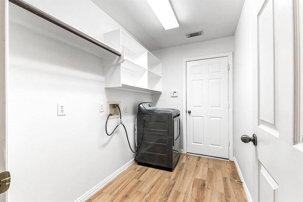 The large walk-in laundry room on the main floor is equipped with shelving and hanging rods, offering ample storage and organization space for all your laundry needs, with easy access to the 2-car garage.