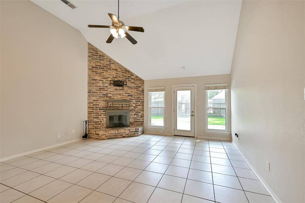 Spacious living room looks out on backyard and includes a brick fireplace.