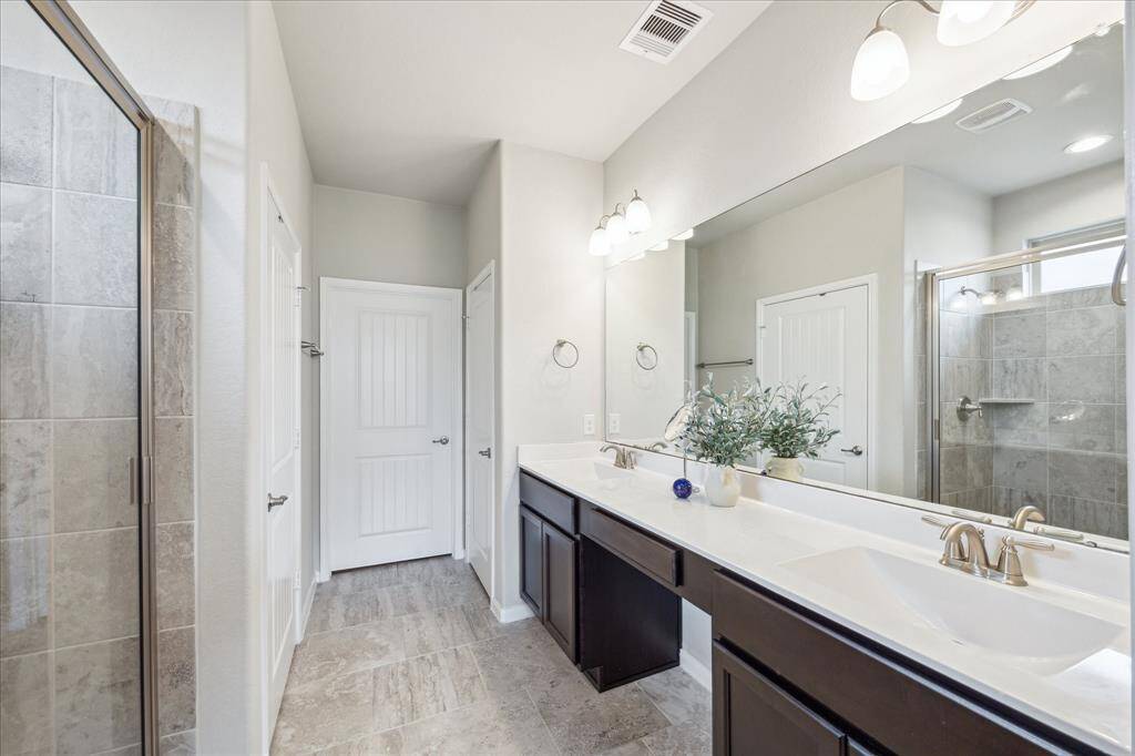The primary bedroom's ensuite bath has an oversized luxurious shower, private water closet, dual sinks and vanity seating space.