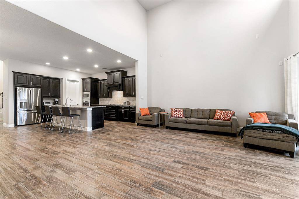 Experience open-concept living that seamlessly connects the living room, breakfast bar, and formal dining room. Enjoy the lofty ceilings, stunning windows, and a stylish drop-down ceiling fan. The spacious living area easily accommodates a variety of furniture layouts, offering both comfort and flexibility.
