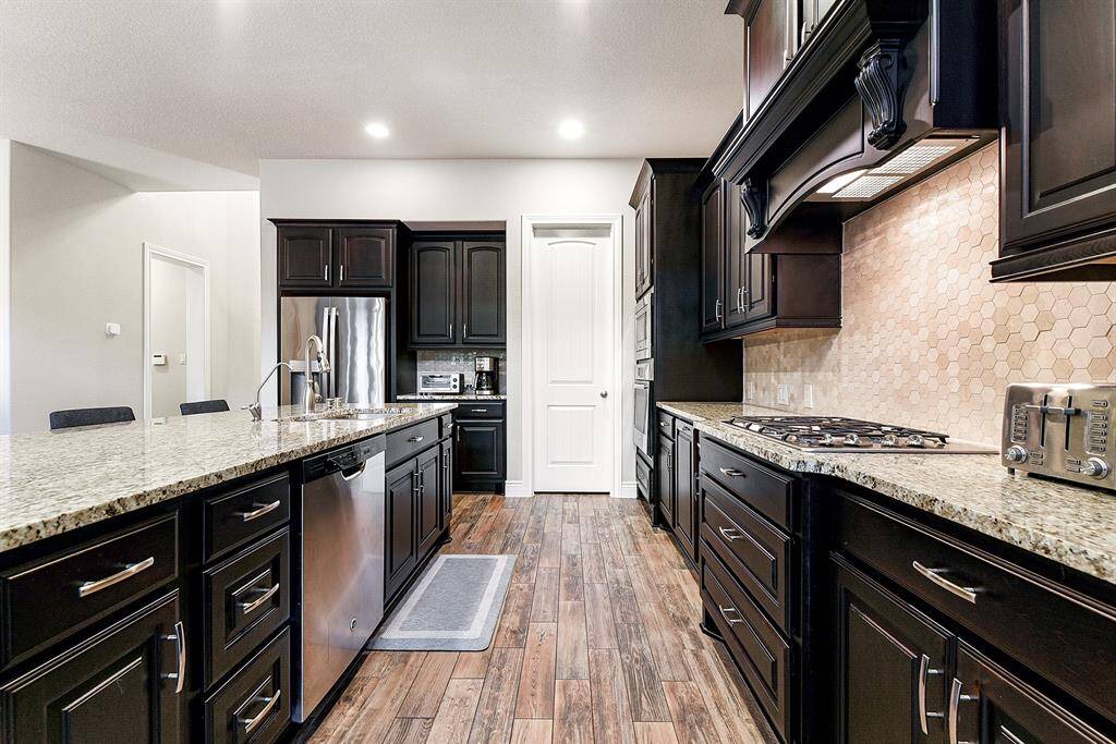 As you enter the kitchen from the foyer, you’ll encounter a masterpiece featuring rich cabinetry with convenient pull-out shelves that enhance both functionality and elegance. The kitchen showcases the expansive granite countertops, a gas stove, wall oven, and microwave. A large walk-in pantry next to the refrigerator includes the perfect coffee nook.