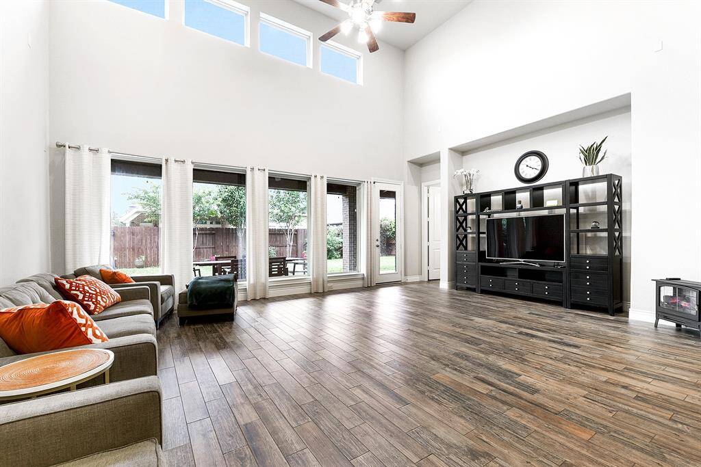 The wall of windows includes a back door that opens to the full-length extended patio, perfect for hosting celebrations and enjoying outdoor living. Notice the consistent wood-look tile flooring throughout the entire home, creating a cohesive and stylish feel in every room. Tucked into the right corner of the home is the private owner's retreat, offering comfort and seclusion.