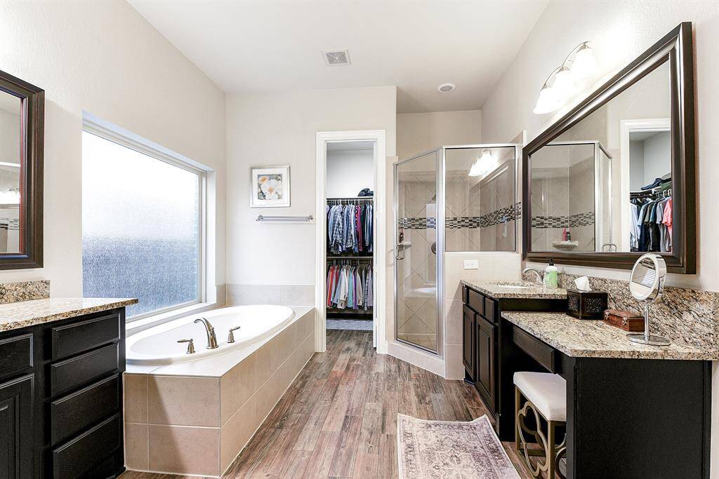 The primary en suite bathroom has it all—offering generous space with two separate vanities, one featuring a built-in prep seating area. Enjoy a relaxing garden bathtub, a spacious tiled walk-in shower, and large walk-in closets for ample storage.