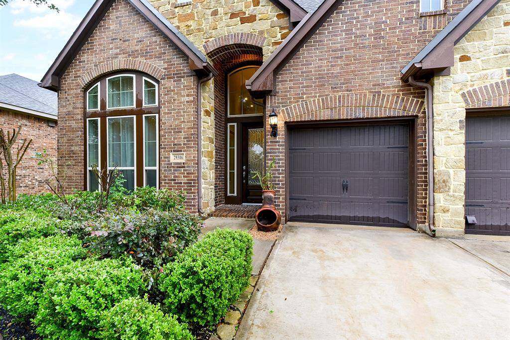 Another view of this home's impressive front yard highlights the upgraded exterior, featuring a striking combination of brick and stone elevation.