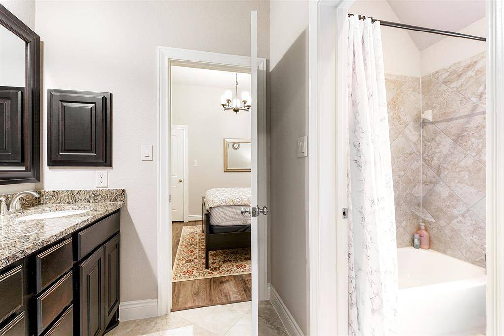 This angled view provides a better idea of the shared two-piece bathroom between the two guest rooms, featuring a shower/tub combo. Each room has its own door to the double sink vanity, which includes cabinetry for ample storage.