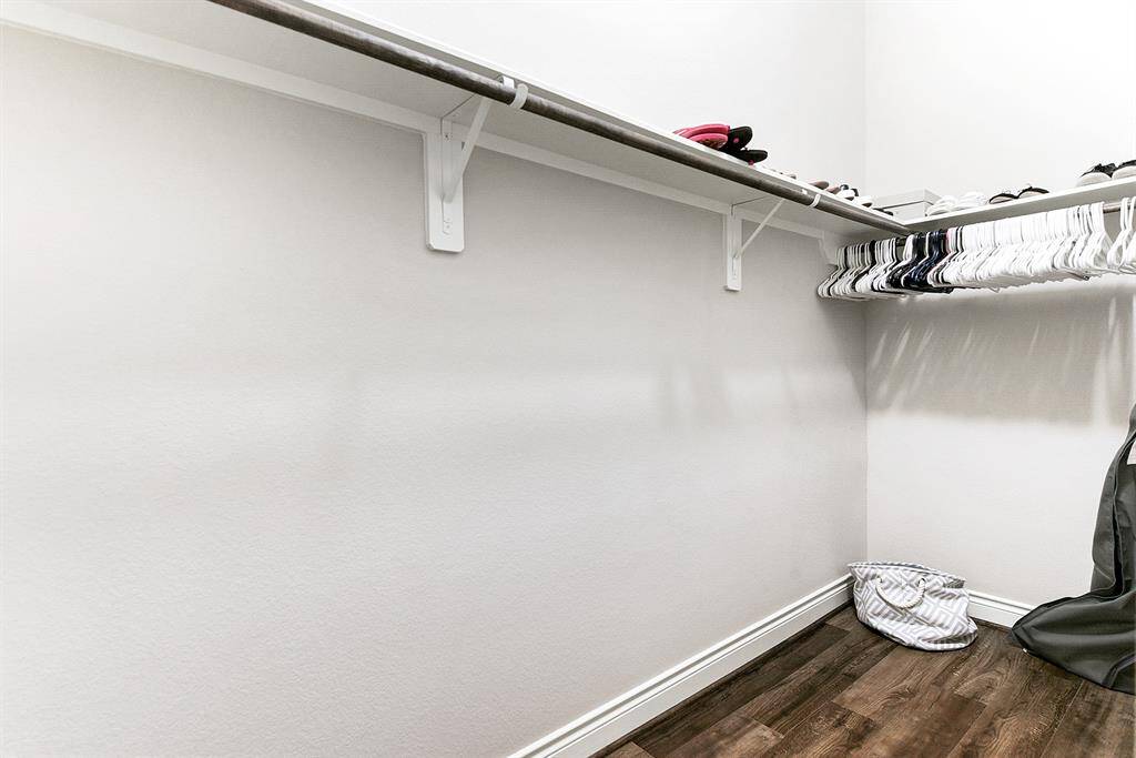 This room offers a large guest walk-in closet with hanging rods and shelving. The main closet features carpet-free flooring for easy maintenance.