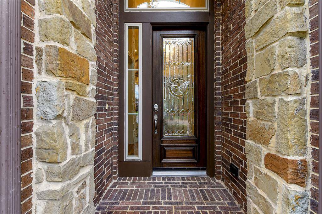 An inviting front yard with a covered patio welcomes you to the home, where the entry showcases all-brick flooring and a beautiful wood front door with keyless entry for added convenience.