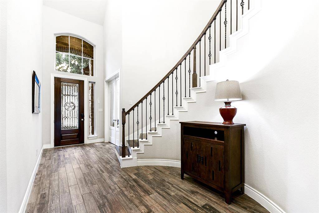 A welcoming foyer with elevated ceiling heights and a curved staircase offers a grand view of the front door, creating an inviting and elegant entryway.