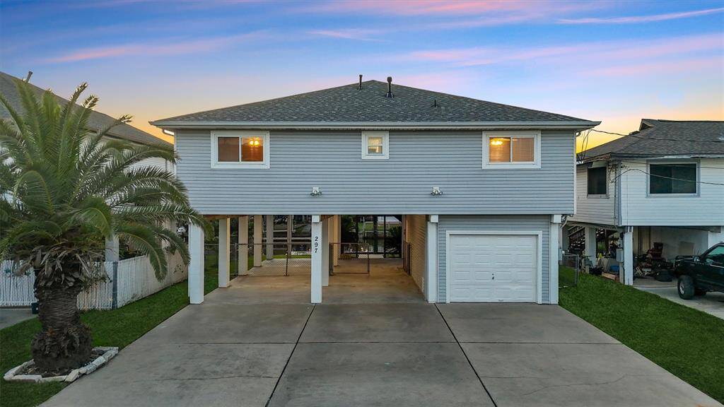 Clean and coastal curb appeal with fresh siding, a wide driveway, and covered parking. Elevated construction offers peace of mind and added space below for storage or entertaining.