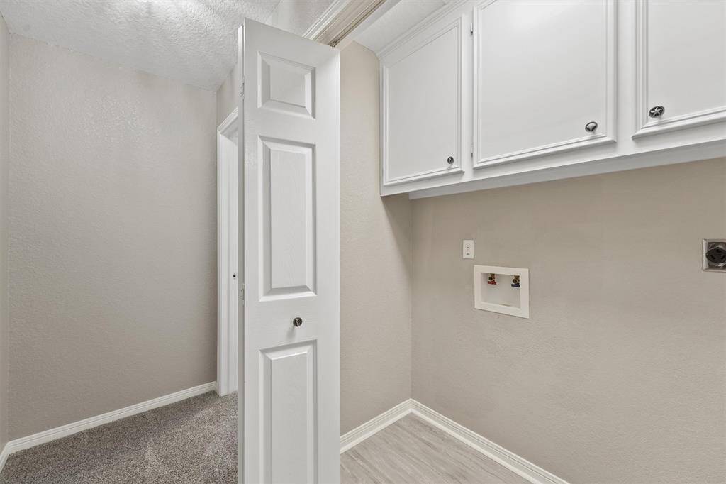 Dedicated laundry room with upper cabinetry, fresh paint, and room for full-size washer and dryer.