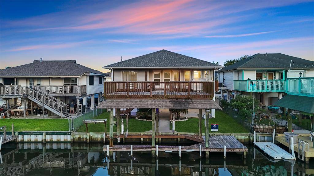 Back of the home glows under a vibrant sunset, highlighting the oversized deck and canal-side serenity.