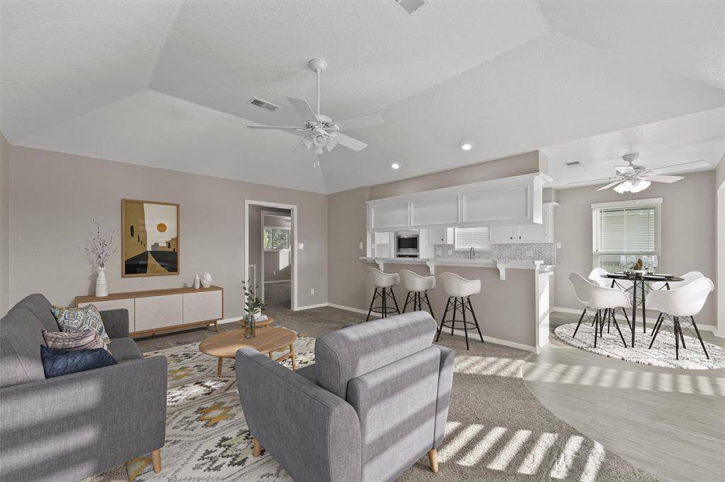Bright and inviting open-concept layout featuring vaulted ceilings, recessed lighting, and neutral finishes. Ideal for hosting or relaxing with water views through the windows.