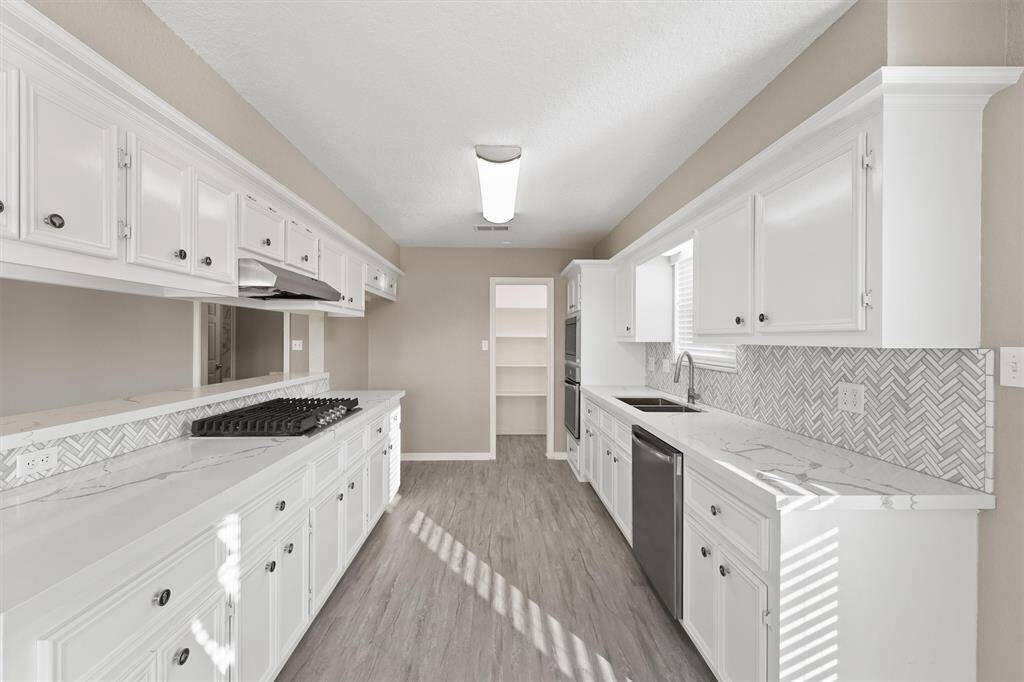Updated kitchen with white cabinetry, new countertops, and a gorgeous herringbone tile backsplash. Includes built-in appliances, breakfast bar seating, and luxury vinyl plank flooring.