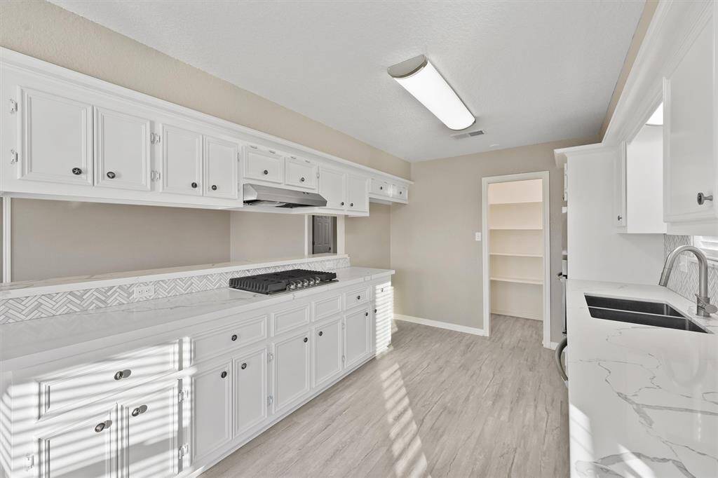 Ample counter space and cabinetry with a clean, timeless look. Open shelving nook and pantry access make it both functional and stylish.
