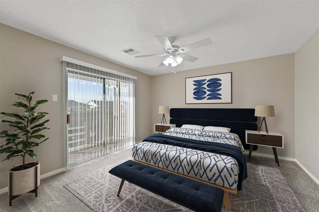 Spacious bedroom with plush carpeting, vaulted ceilings, and direct access to a private balcony through sliding glass doors.