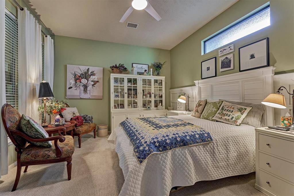 Secluded primary bedroom at the rear of the home features tall wainscoting detail and premium carpet.