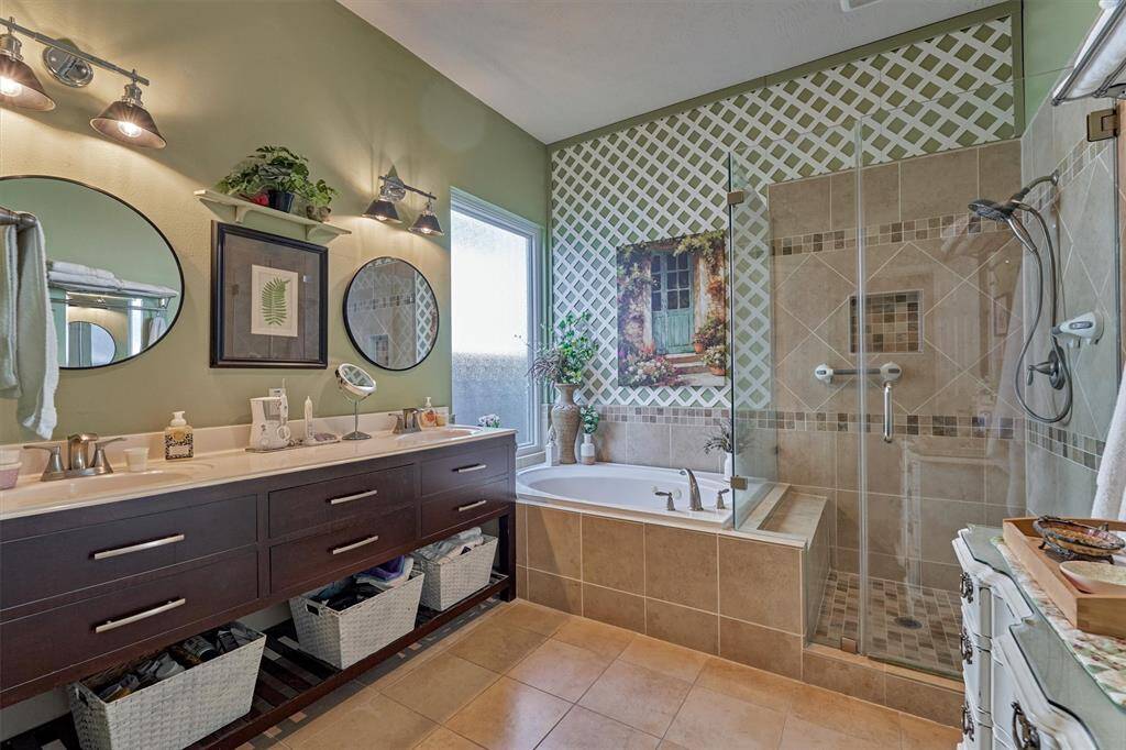 Magazine-worthy primary bath offers oversized vanity with dual sinks, seamless shower surround and jacuzzi tub.