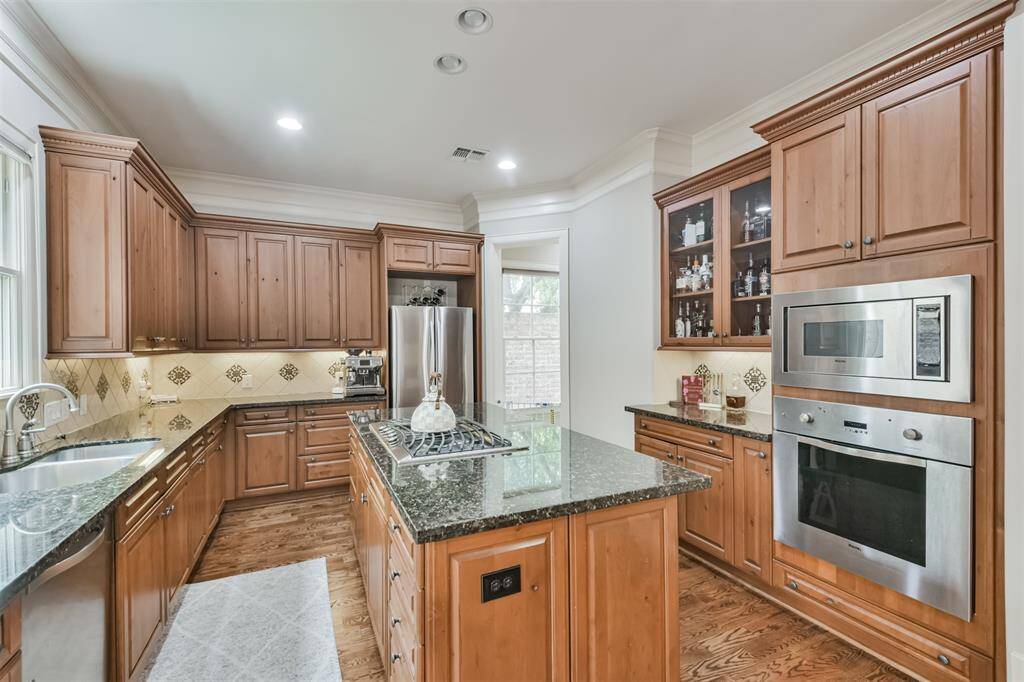 Chef's kitchen features rich woodcabinetry, granite countertops, alarge island with gas cooktop,and built-in stainless steelappliances—perfect for culinarycreativity and effortlessentertaining.